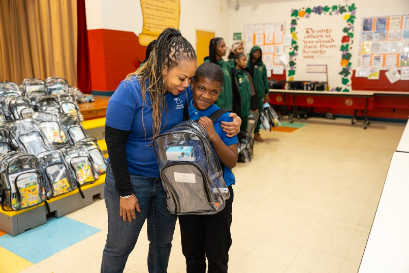 Avant warmly embraces a student at an annual backpack drive at Larose Elementary.